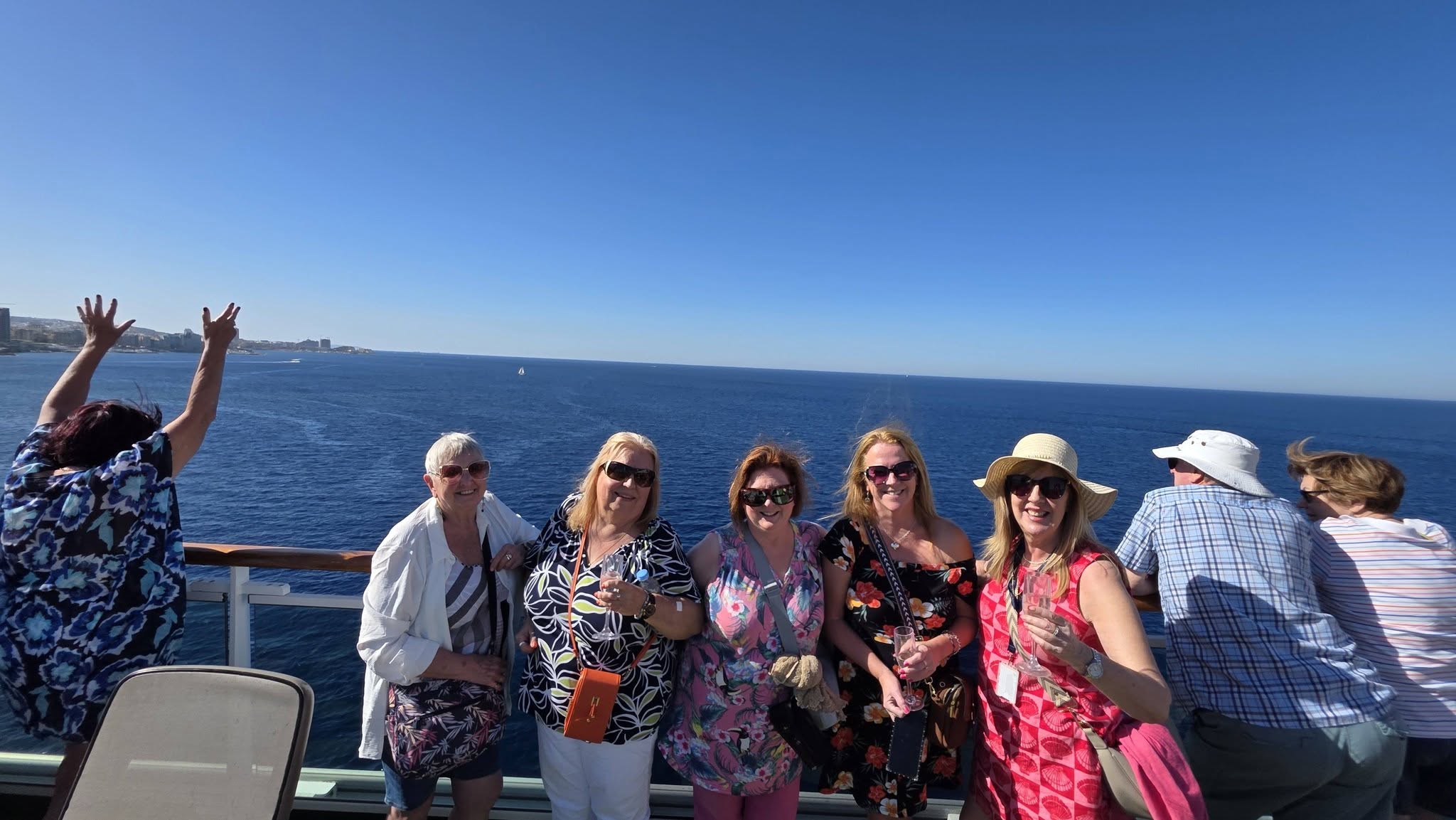 Solo travellers together on Azura’s open deck under a blue sky