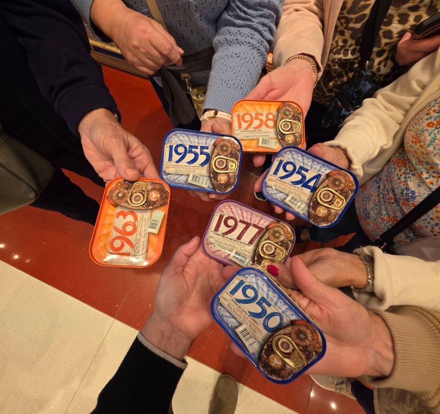 Travellers holding colourful sardine tins marked with different years