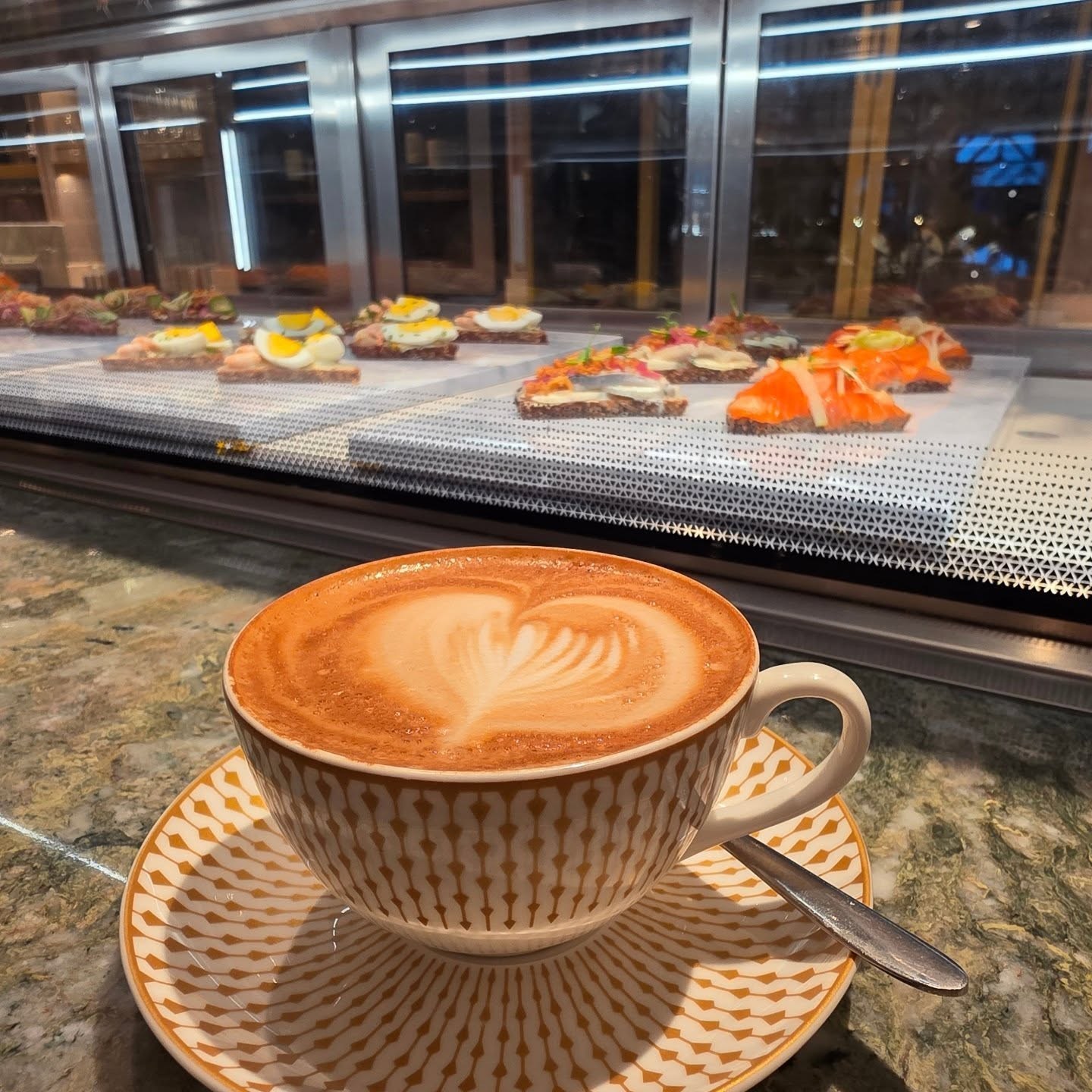 A latte in a patterned cup beside the café counter