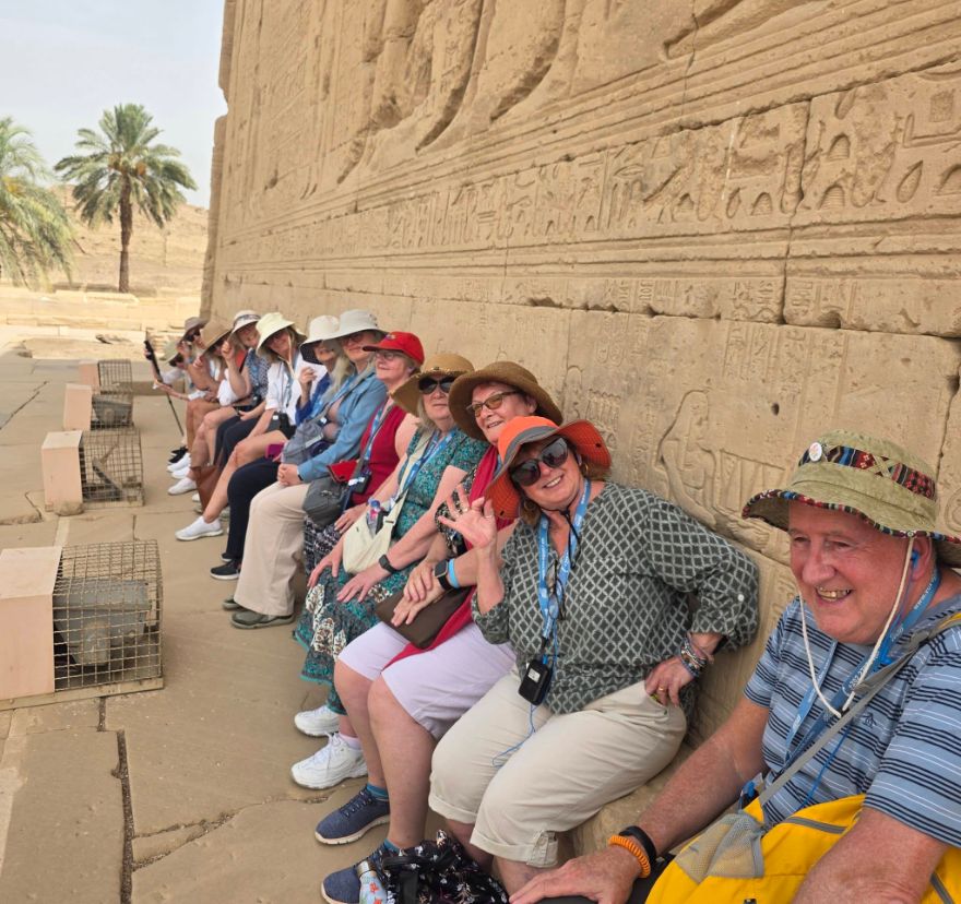 Our hosted group resting beside a carved temple wall at Dendera