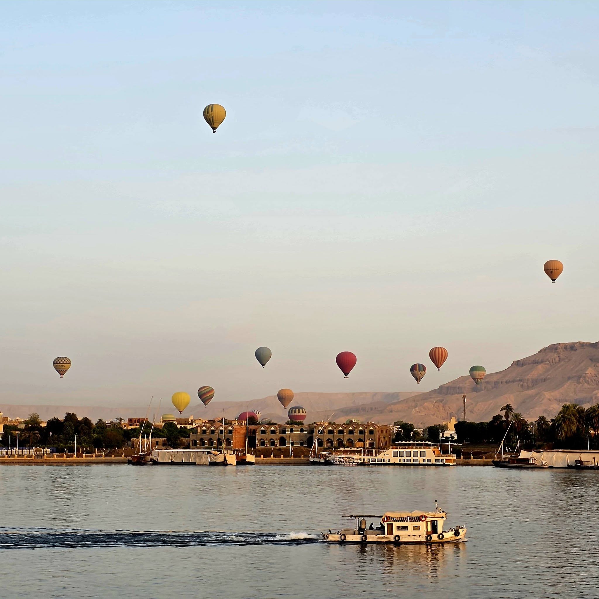 Hot-air balloons over Luxor with a small boat on the Nile