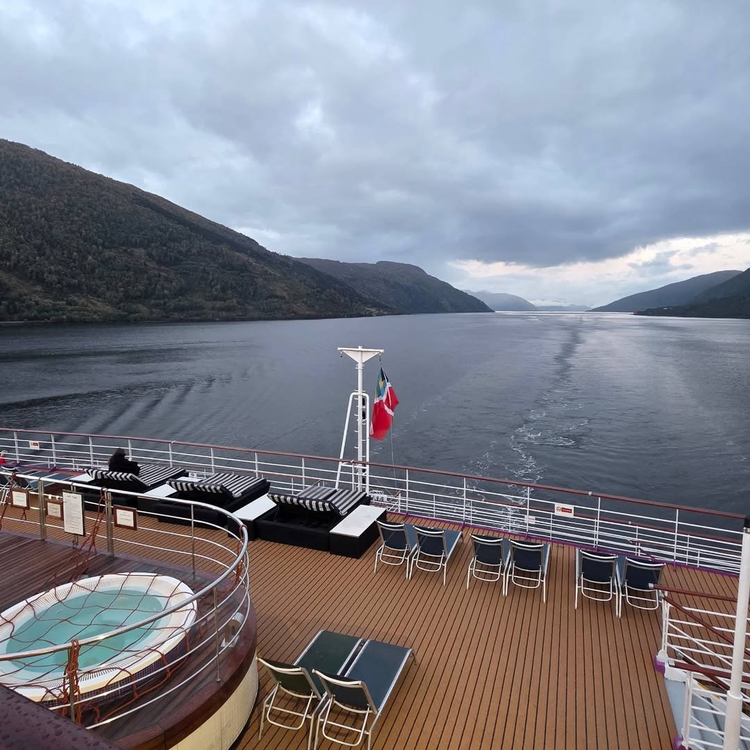 Broad fjord view above the ship’s pool and loungers.