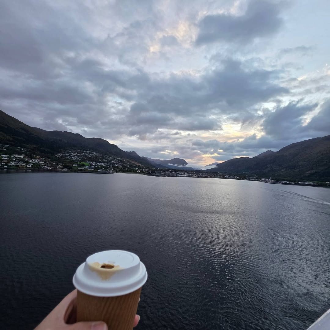 Takeaway coffee in the foreground of a fjord panorama.