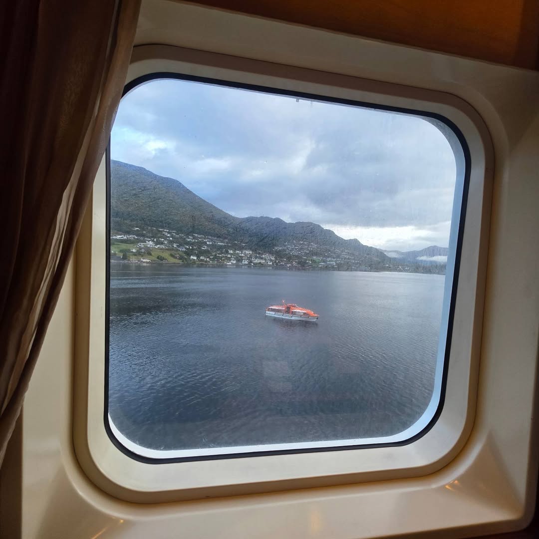 Norwegian fjord and nearby settlement framed by a cabin window.